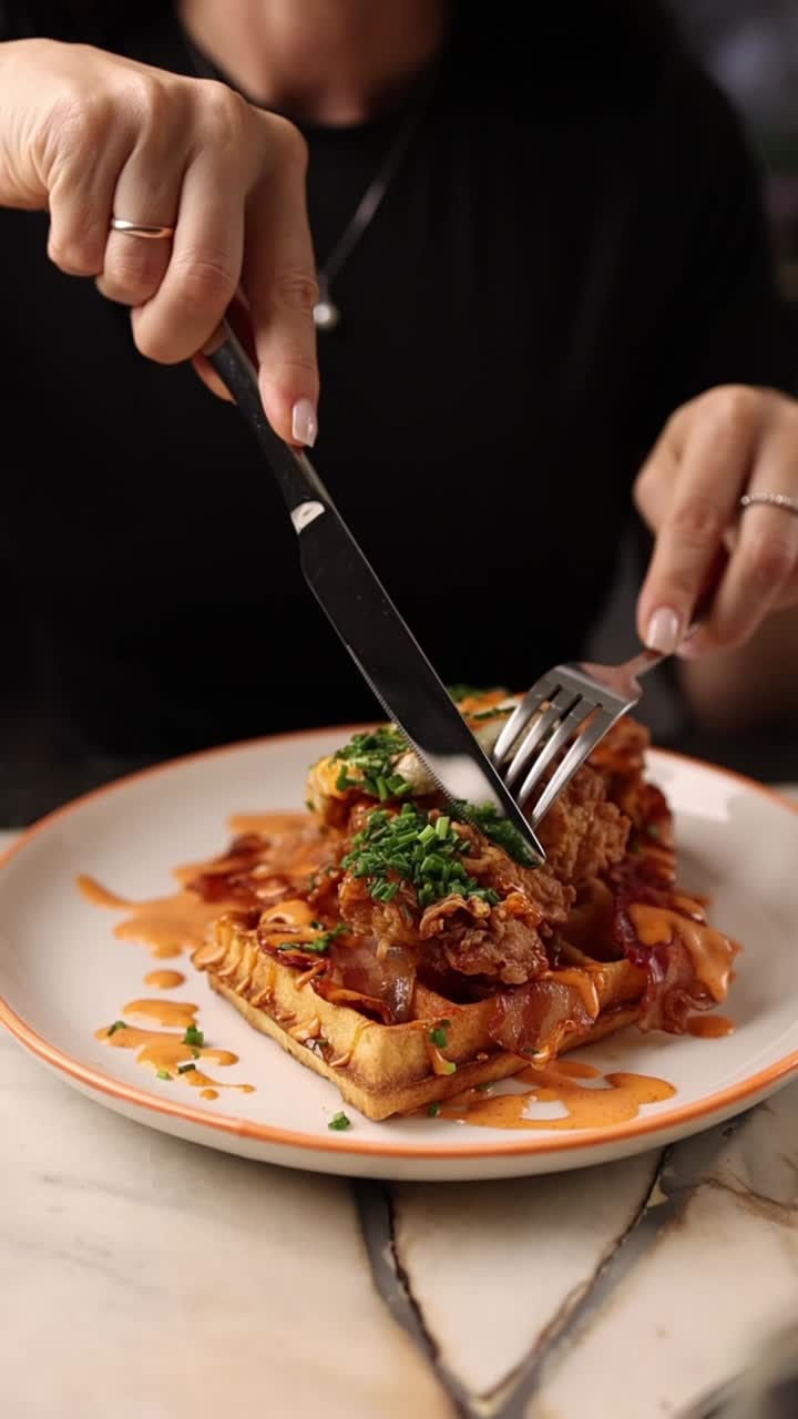 Person Cutting into Delicious Chicken and Waffles Dish
