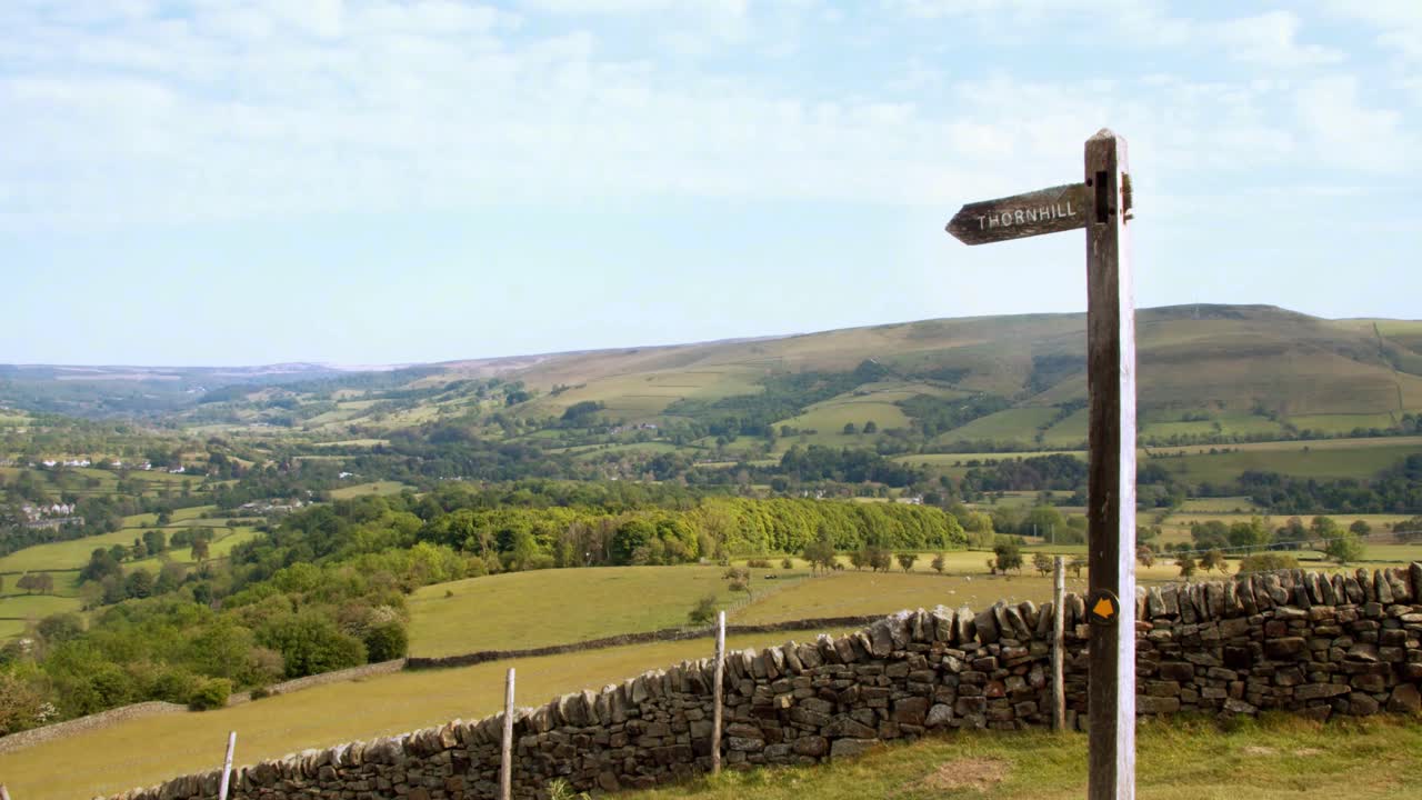 timelapse de nubes moviéndose sobre el pintoresco campo con un cartel de madera en primer plano