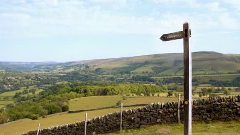 Timelapse-of-clouds-moving-over-the-picturesque-countryside-with-a-wooden-signpost-in-the-foreground