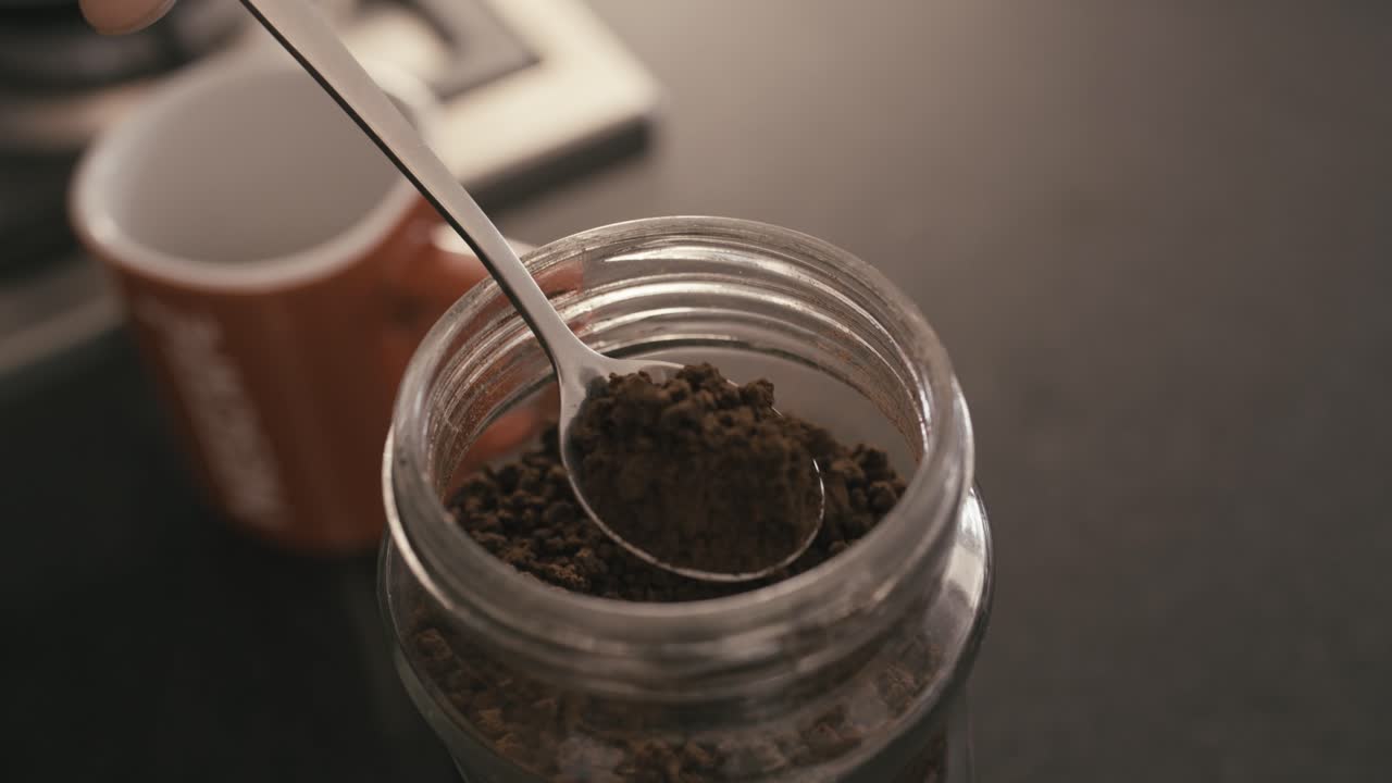 person scooping fresh coffee with a spoon and placing it into the cup with precision and conviction.