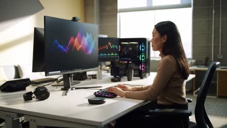 a focused individual engaged in data analysis at a modern workspace featuring high-tech monitors and keyboards