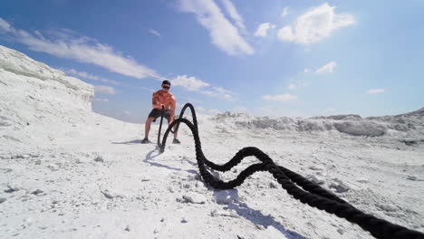 man workout on nature. sporty man doing exercise with battle ropes while working