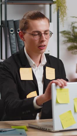 tired exhausted businessman with laptop sticky notes with many tasks sitting at home office desk