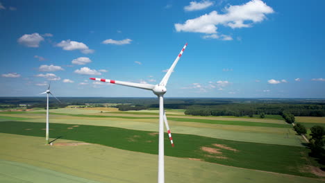 aerial close-up giant wind turbine with rotating blades in a vast, agricultural field actively generating green power energy