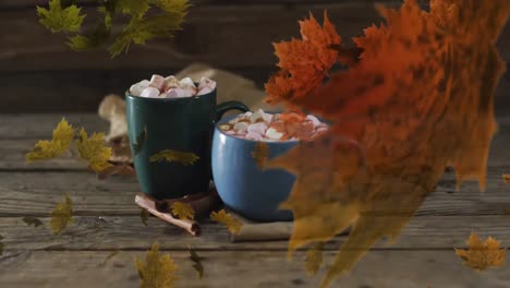 animation of leaves over mugs with cocoa on wooden background