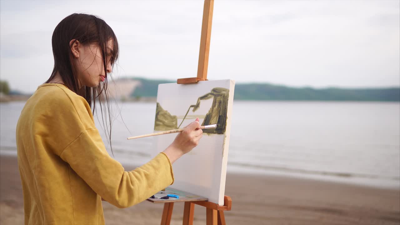 Woman painting a landscape on a beach