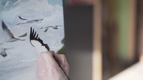 close up footage of painters hands adding black watercolour with brush on flying stork birds painting in painting academy