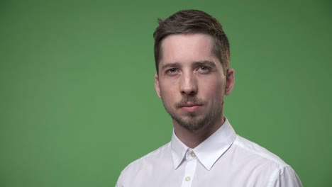 un joven serio con una camisa blanca gira la cabeza, la clave de croma de fondo de pantalla verde