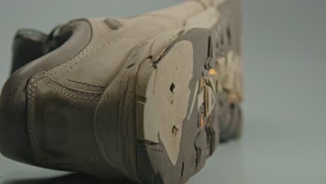 una bota de senderismo desgastada se encuentra en un fondo de estudio blanco