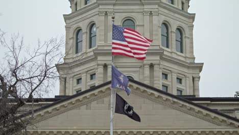 Fahnen-Wehen-In-Zeitlupe-Vor-Dem-Kansas-State-Capitol-Building-In-Topeka,-Kansas,-Mit-Stabilem-Nahaufnahmevideo