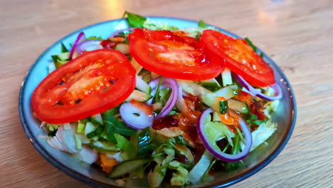 pullback from fresh mediterranean salad with bright red tomato slices, red onions, cucumbers, and fresh lettuce