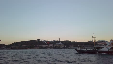 evening, cinematic slow-mo, a ferry sailing through the bosphorus in istanbul, with the kizilay building and hagia sophia mosque visible in the background