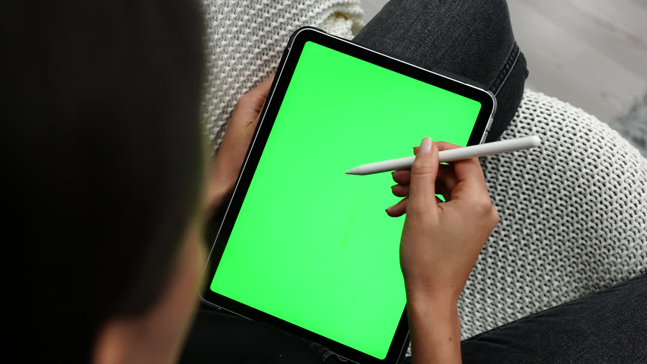 tableta con pantalla verde y mano femenina sosteniendo un lápiz óptico en la pantalla táctil, primer plano