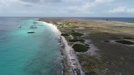 drone volando sobre la costa de coral rocoso con agua clara del océano isla privada con barcos ankered