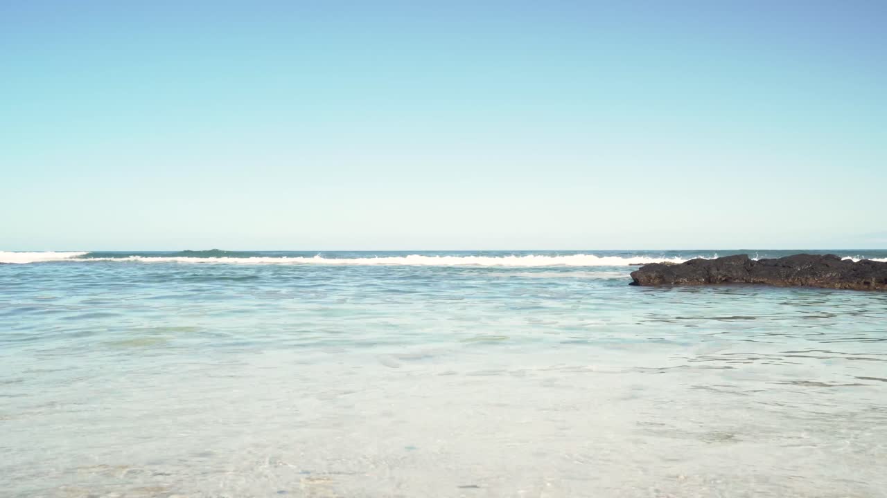 백사장 앞의 용암 암석을 때리는 큰 파도