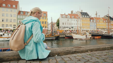 a woman strolls along the canal against the background of famous colorful houses the most popular pl