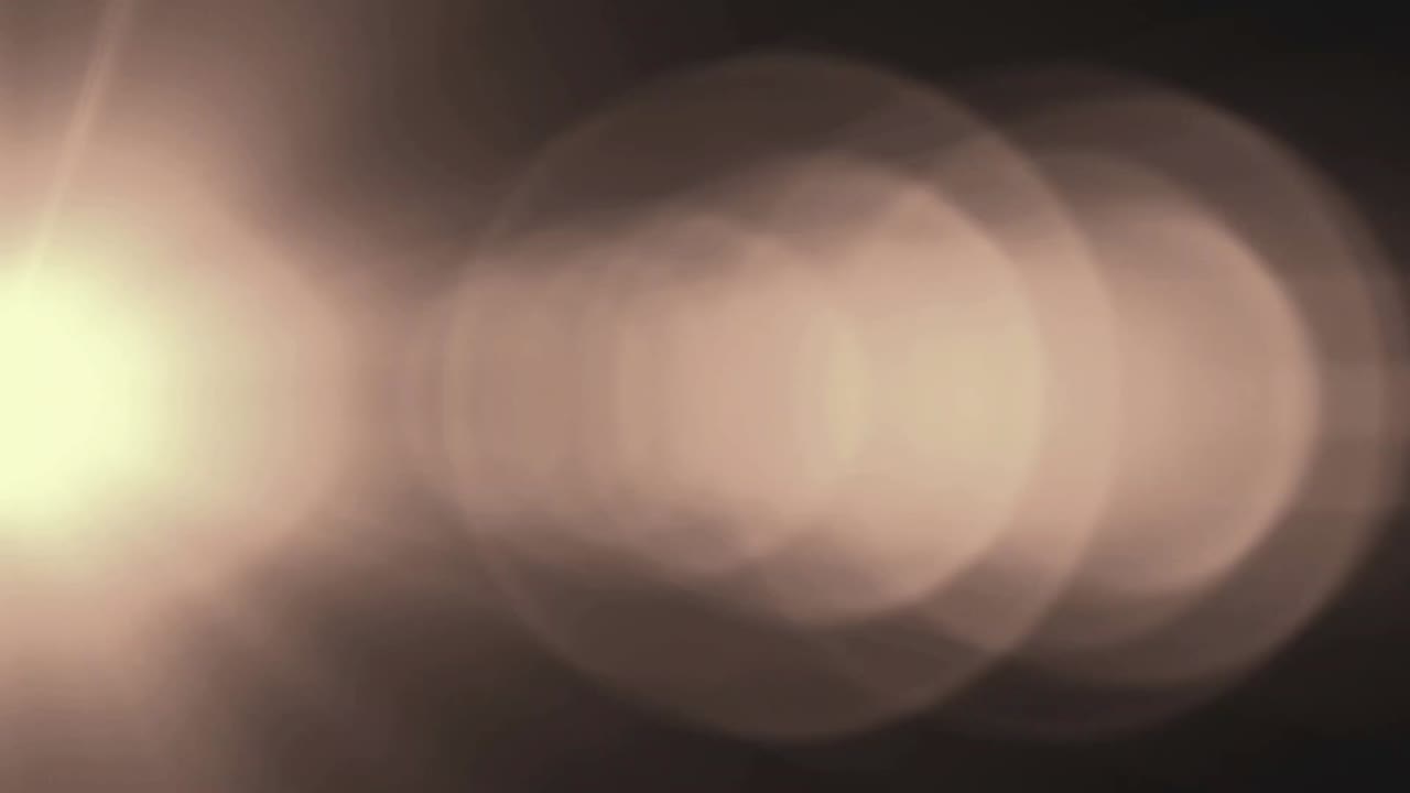 Warm Light Lens Flare and Bokeh Moving Across Dark Background