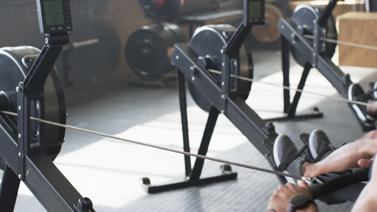 Using rowing machine, man exercising in gym, focusing on fitness and strength