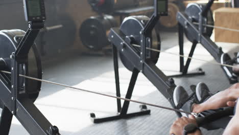 using rowing machine, man exercising in gym, focusing on fitness and strength
