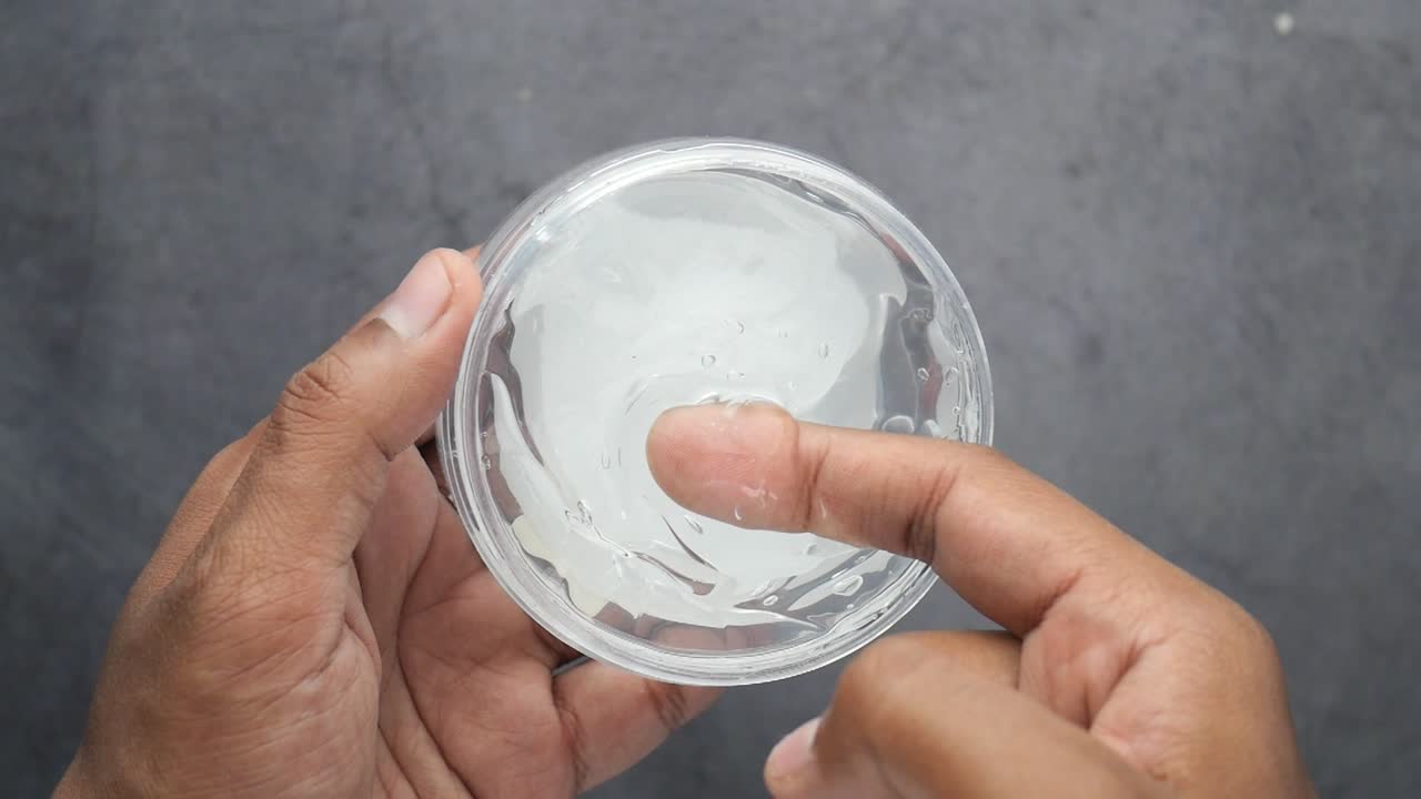 la mano sostiene un frasco de gel para el cabello