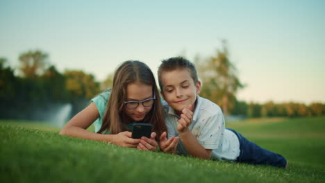 Thoughtful-boy-looking-away-in-summer-field.-Pretty-girl-typing-phone-outdoors