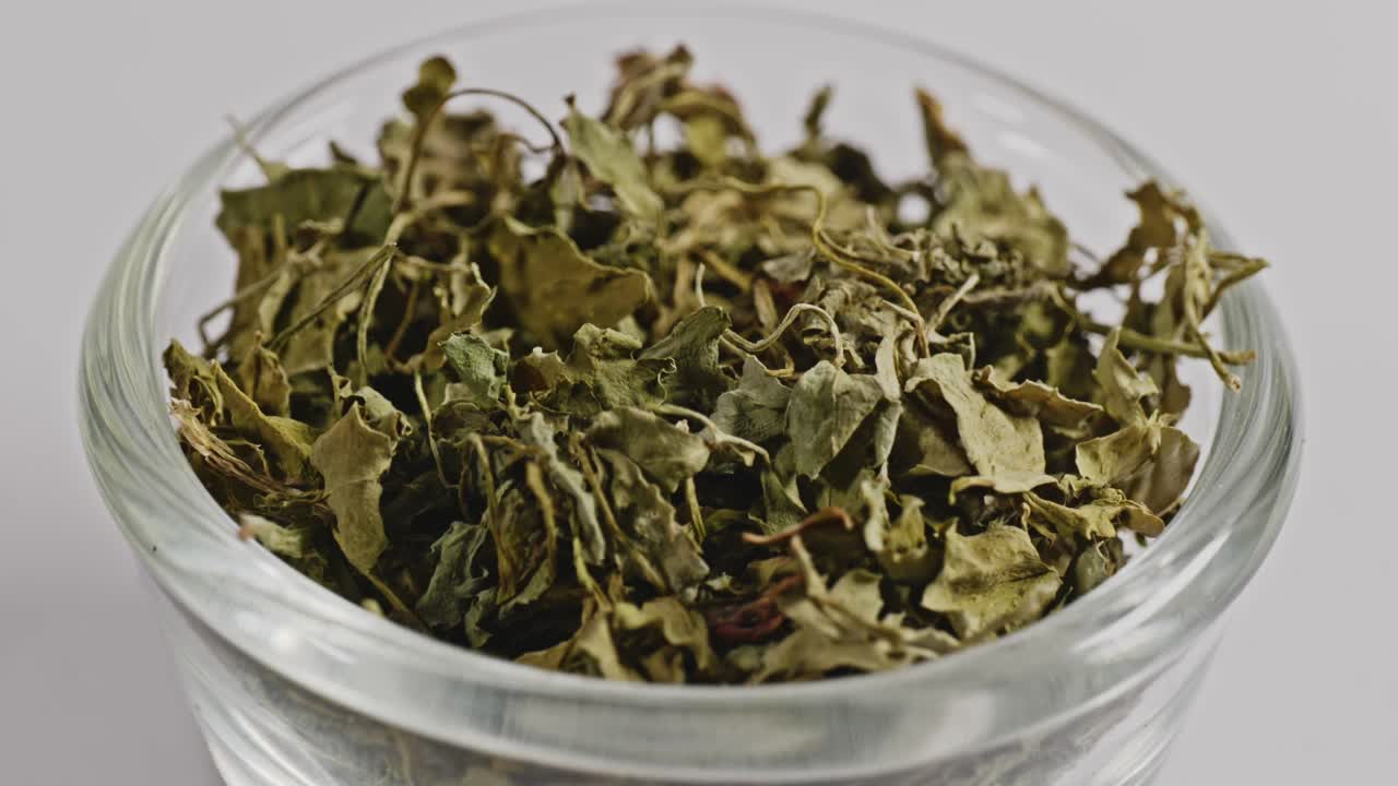 dried fenugreek leaves or Kasuri methi in small glass bowl, 4k, stable shot