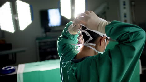 cirujana biracial con máscara facial en el quirófano del hospital, cámara lenta