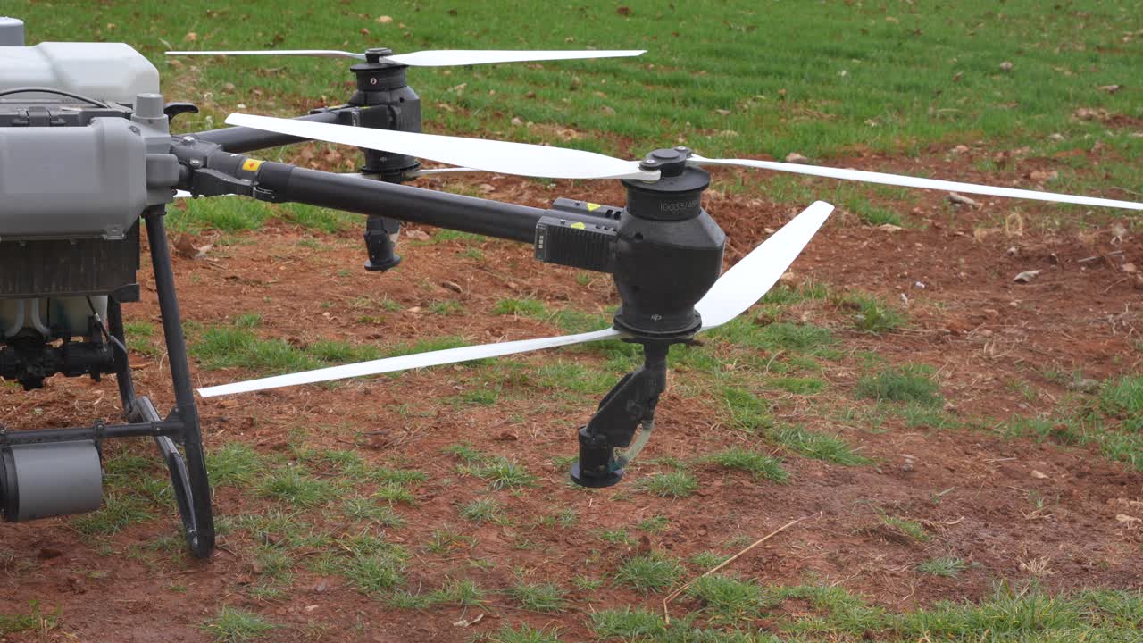 Close up shows agricultural drone arm releasing water vapor during preflight test near wheat field