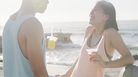 Happy-biracial-couple-drinking-juice-on-promenade,-in-slow-motion