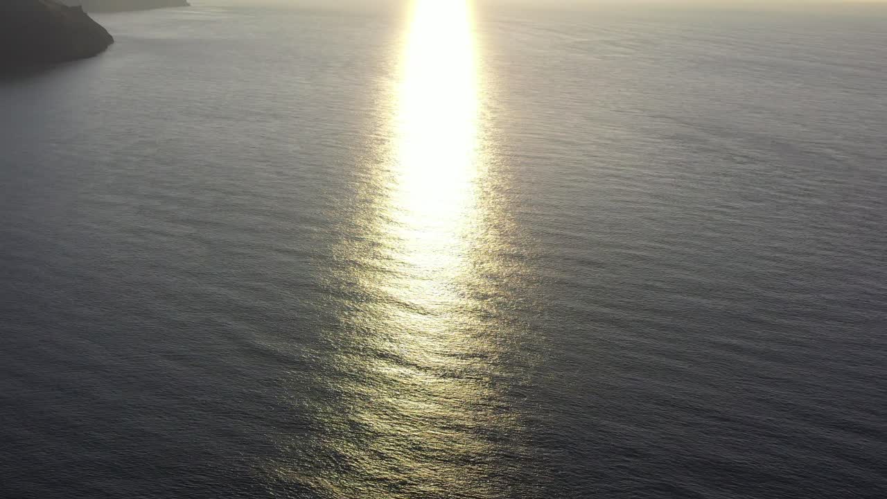 Drone shot looking at the refection of sun rays on the ocean from sunset on the North Devon coast in the UK
