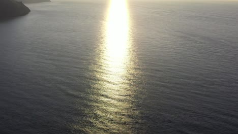 drone shot looking at the refection of sun rays on the ocean from sunset on the north devon coast in the uk