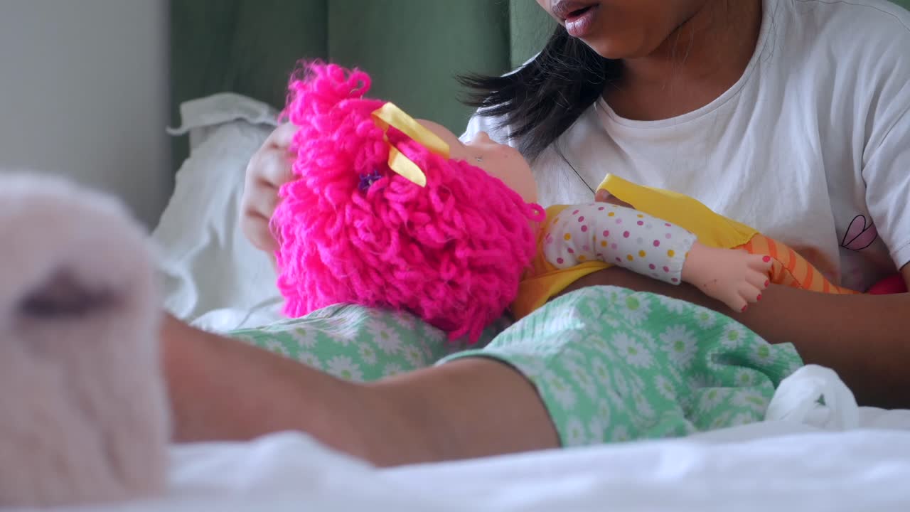 Girl playing with a doll in bed