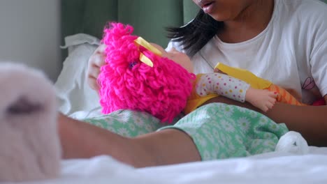 girl playing with a doll in bed