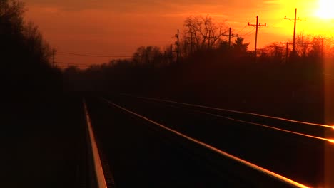 Ein-Strahlender-Goldenhour-Himmel-Wirft-Sein-Spiegelbild-Auf-Den-Bahngleisen,-Die-Sich-Bis-Zum-Horizont-Erstrecken