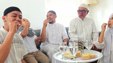 multi generation muslim family enjoy eating snacks and cookies together during eid mubarak in the living room