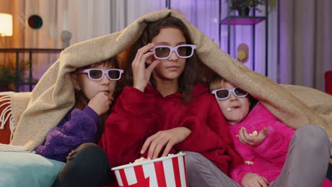 children sits on couch eating popcorn and watching interesting tv serial sport game online at home