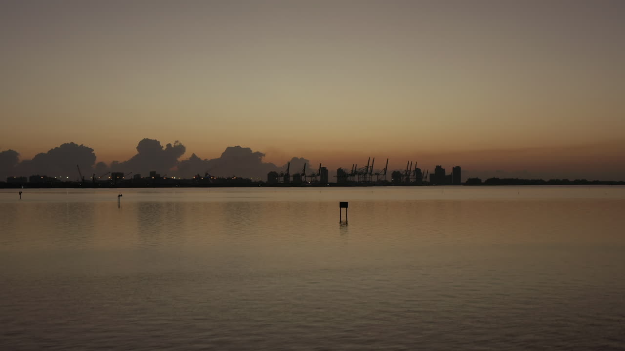 해가 지는 동안 마이애미 해안선에서 하강하는 조감도 선적항 크레인 실루엣 시장