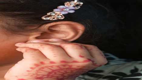 child with henna on hand and hair clip