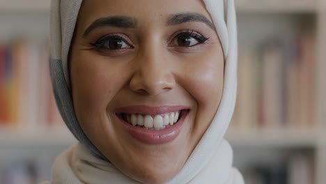 muslim woman student smiling in front of bookshelf