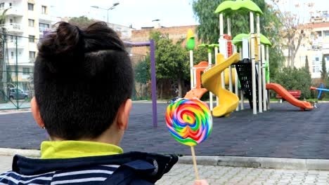 child eating lollipop at the playground