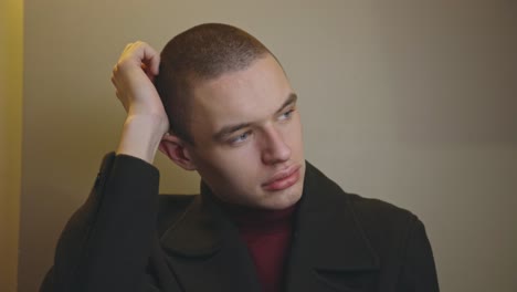 Portrait-Of-A-Young-Sad-Man-Touching-His-Head-While-Leaning-On-A-Wall---Medium-Closeup-Shot