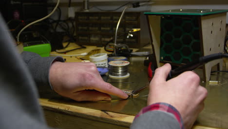 Man-soldering-wire-to-a-circuit-board,-close-up-of-hands,-shot-on-R3D