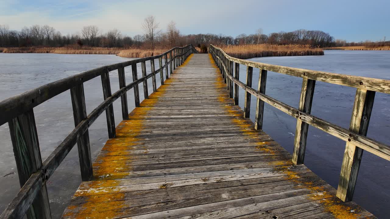 Passerella di legno che conduce sull'acqua gelata della palude a Crosswinds Marsh, Michigan in inverno, USA