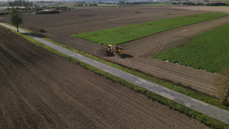 harvester turning on field edge, dumping collected beets - aerial shot