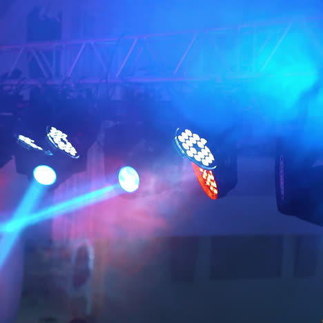 thick smoke and many projectors hanging on the ceiling on the blue blurred background. flashing rays from spotlights in the evening indoors.