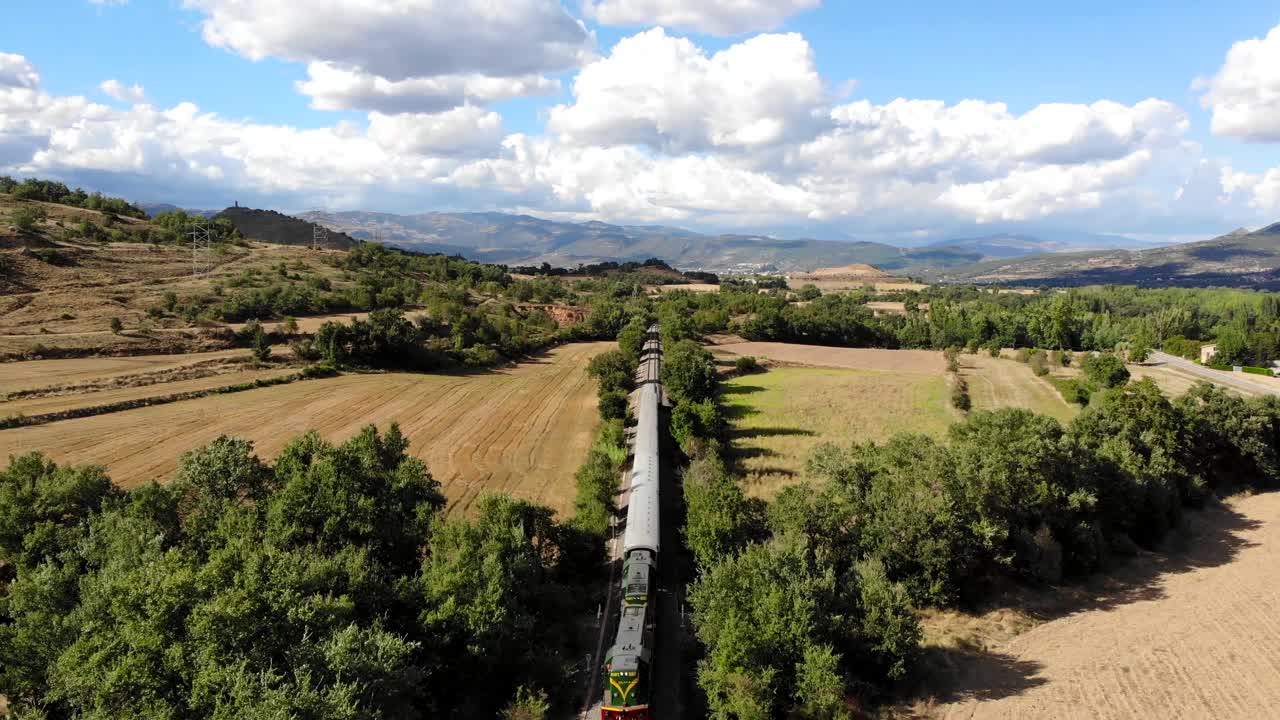antena: viejo tren diesel que viaja a lo largo de los campos bajo el cielo azul de verano con algunas nubes en un día soleado
