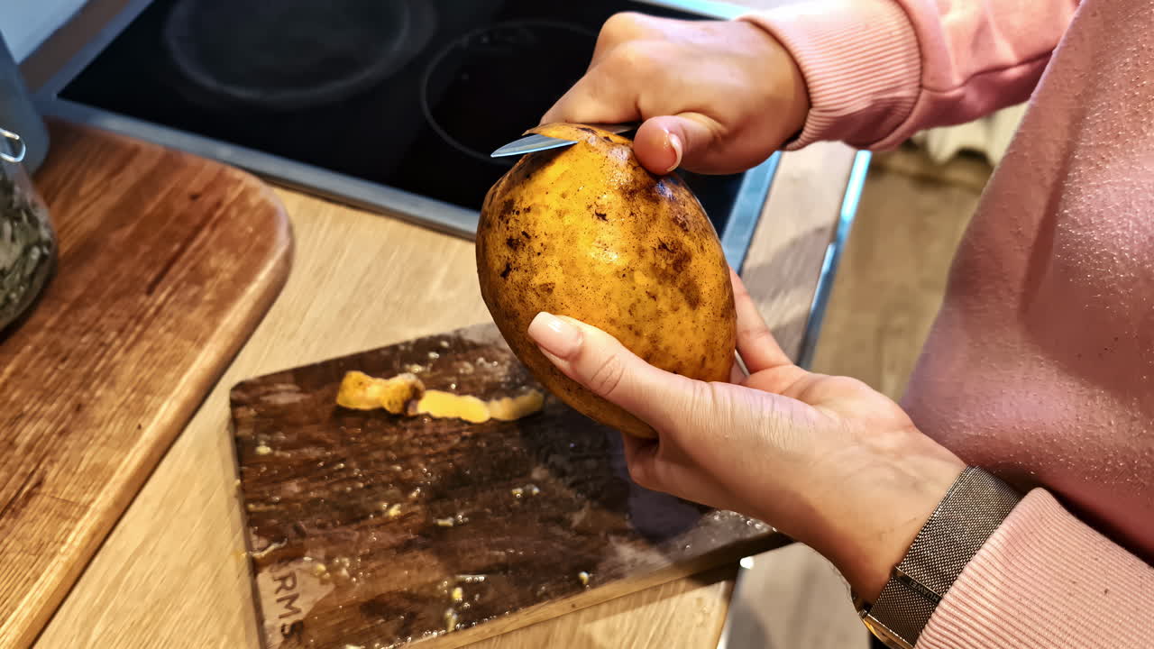 Closeup view of peeling of raw potato by a woman