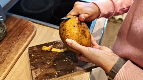 closeup view of peeling of raw potato by a woman