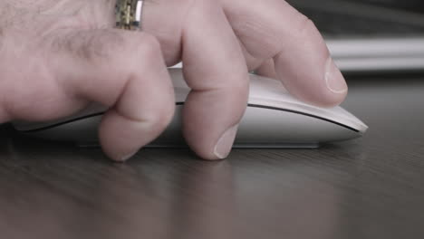 macro shot of executive hand using a mouse next to his laptop computer