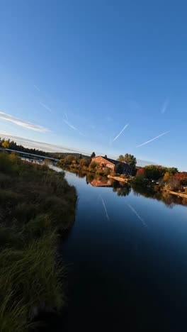 Drone-flys-along-river-in-town-as-birds-pass-overhead